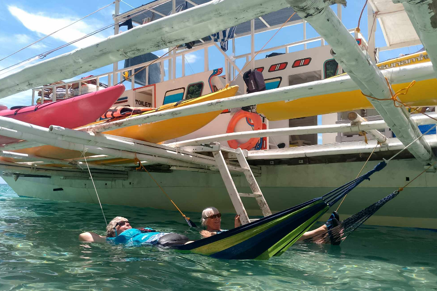 After several kilometers of morning paddle, the ladies deserve a siesta on hammocks strung alongside the native outrigger boat (banca).