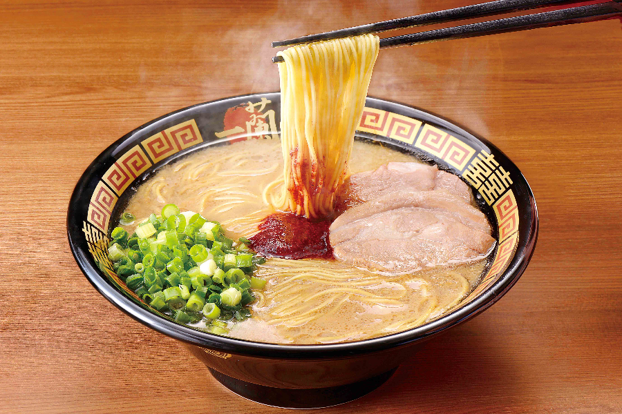 Chopsticks holding noodles from steaming bowl of ICHIRAN Classic Tonkotsu Ramen