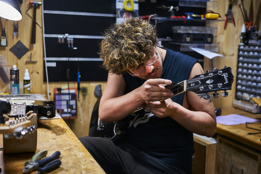 un employé de michel musique en train de réparer une guitare