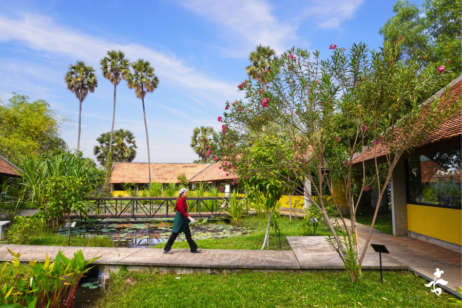 Artisan walks through the tropical garden of the workshop