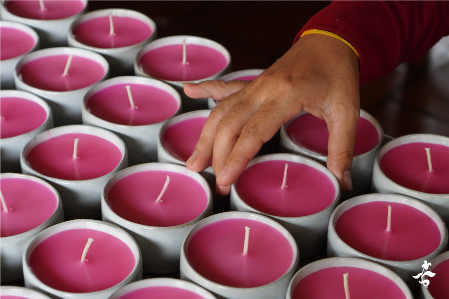 Artisan laying out candles with lotus scents in their ceramic container